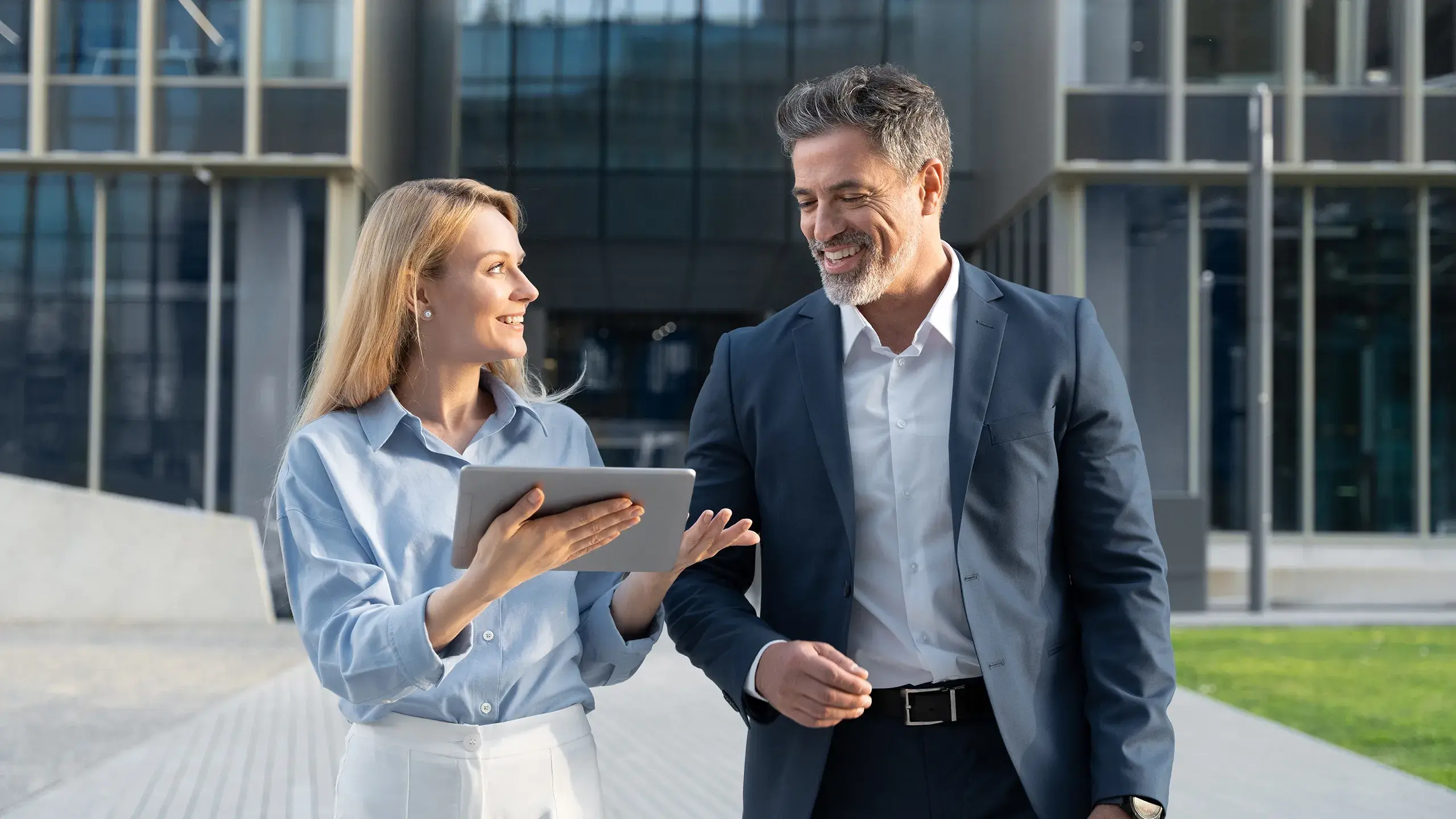 Financial woman and man walking outside discussing tablet